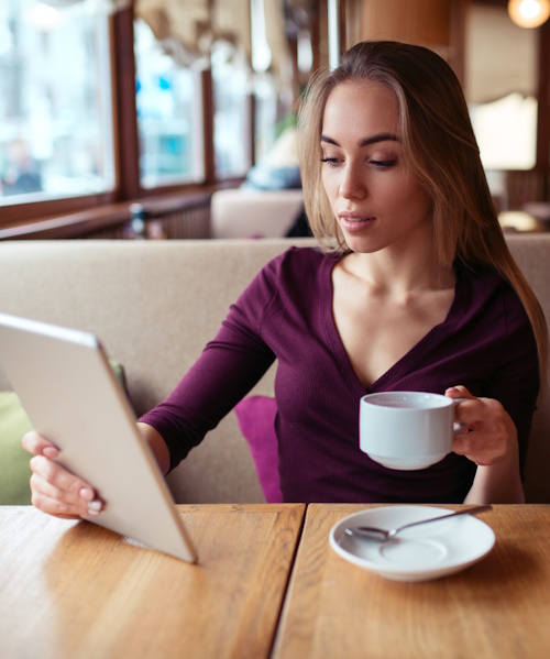 A photo of a woman having a cup of coffee while watching a Youtube video on her computer using the hotel WiFi